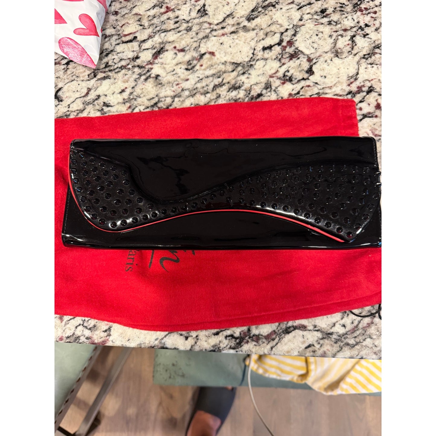 Christian Louboutin Pigalle spiked clutch is crafted from black patent leather and accented with black studs