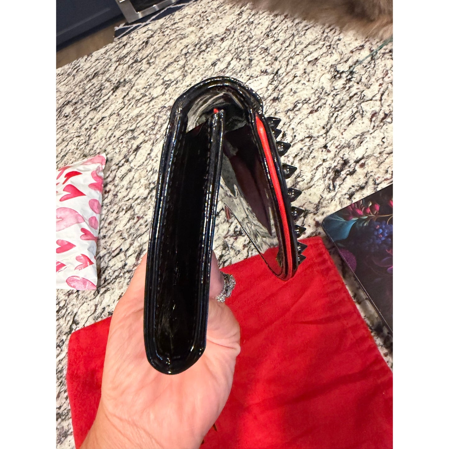 Christian Louboutin Pigalle spiked clutch is crafted from black patent leather and accented with black studs