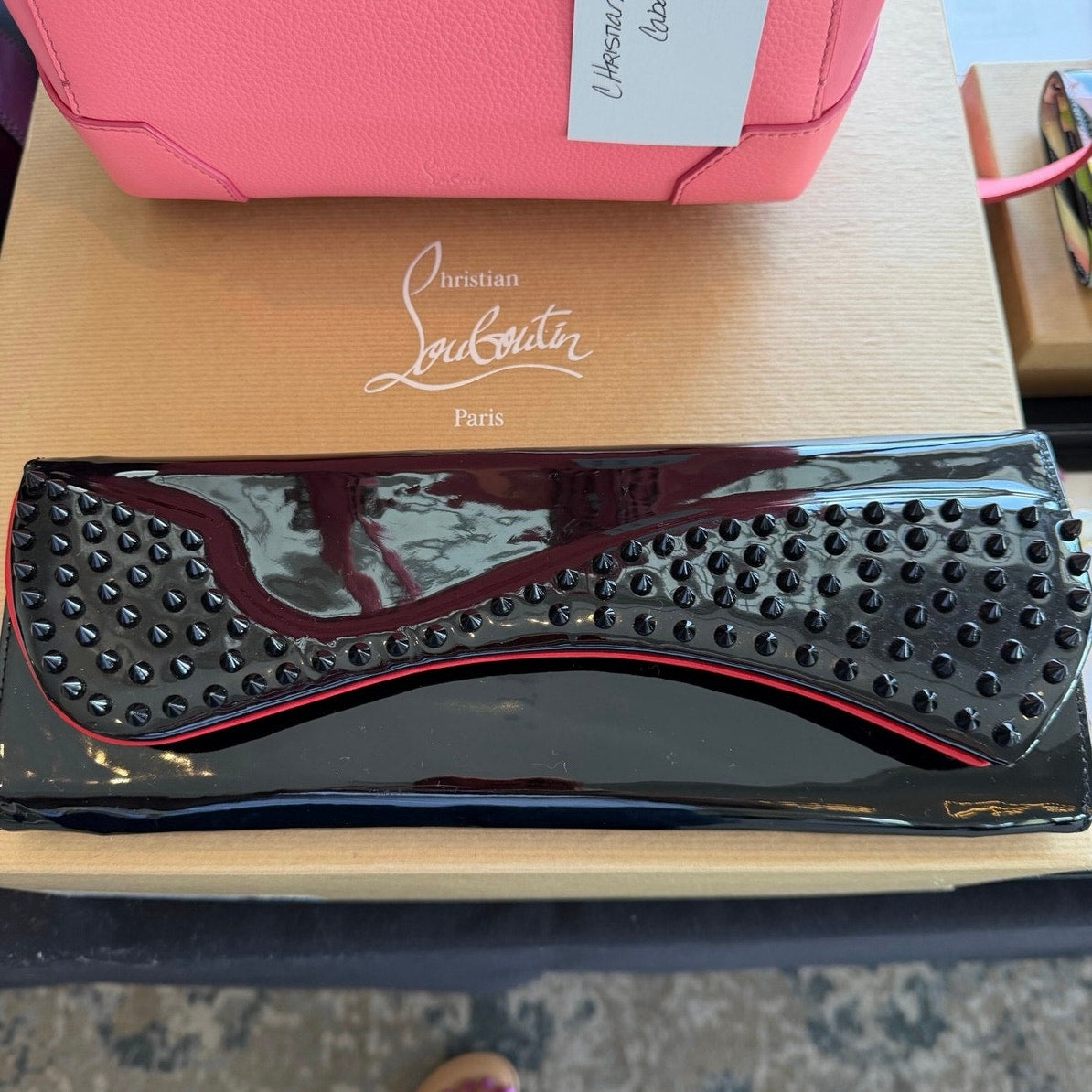 Christian Louboutin Pigalle spiked clutch is crafted from black patent leather and accented with black studs